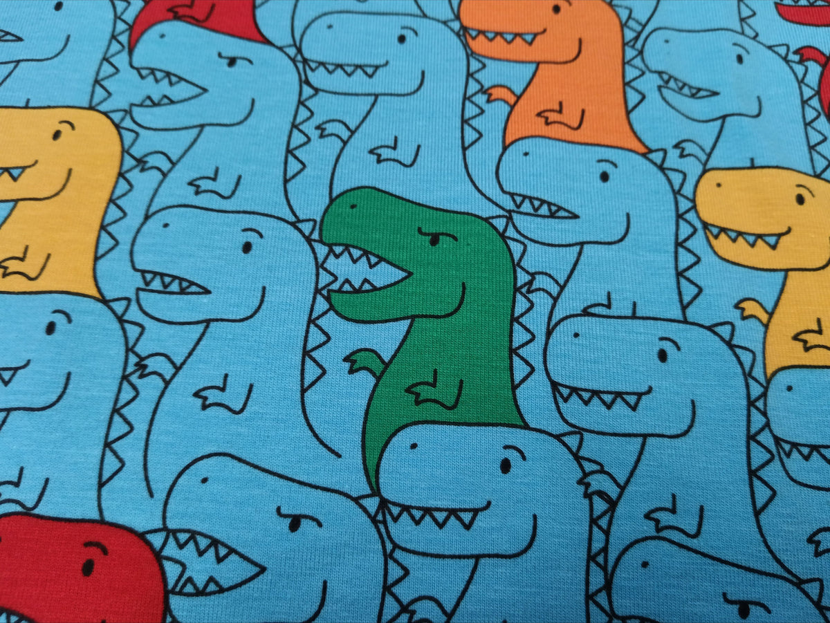 Kinderjersey in blau aus Baumwolle mit bunten Dino Karikaturen - Modemeter Stoffmarkt