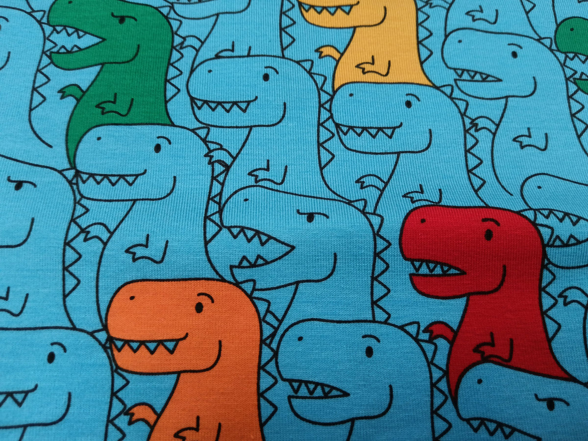 Kinderjersey in blau aus Baumwolle mit bunten Dino Karikaturen - Modemeter Stoffmarkt
